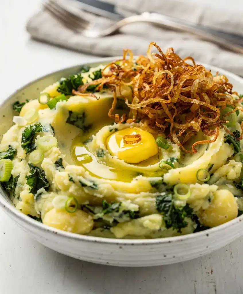 Creamy colcannon potatoes with kale and green onions in a rustic bowl.