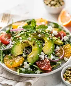 Avocado citrus salad with mixed greens red onion and toasted pepitas