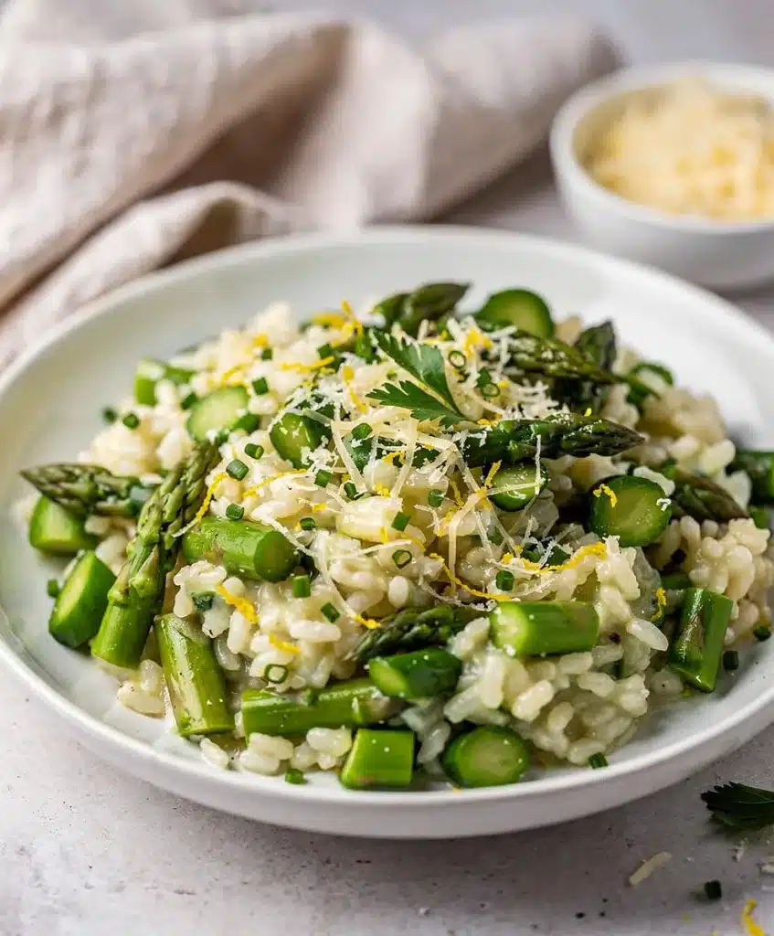 Creamy asparagus risotto with Parmesan in a white bowl on a wooden counter