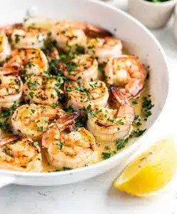 Succulent garlic butter shrimp in a rustic pan with lemon and parsley.