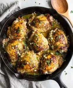 Golden seared garlic herb chicken thighs in glossy pan sauce with parsley