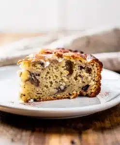 Moist Greek yogurt banana bread slice with walnuts on rustic board