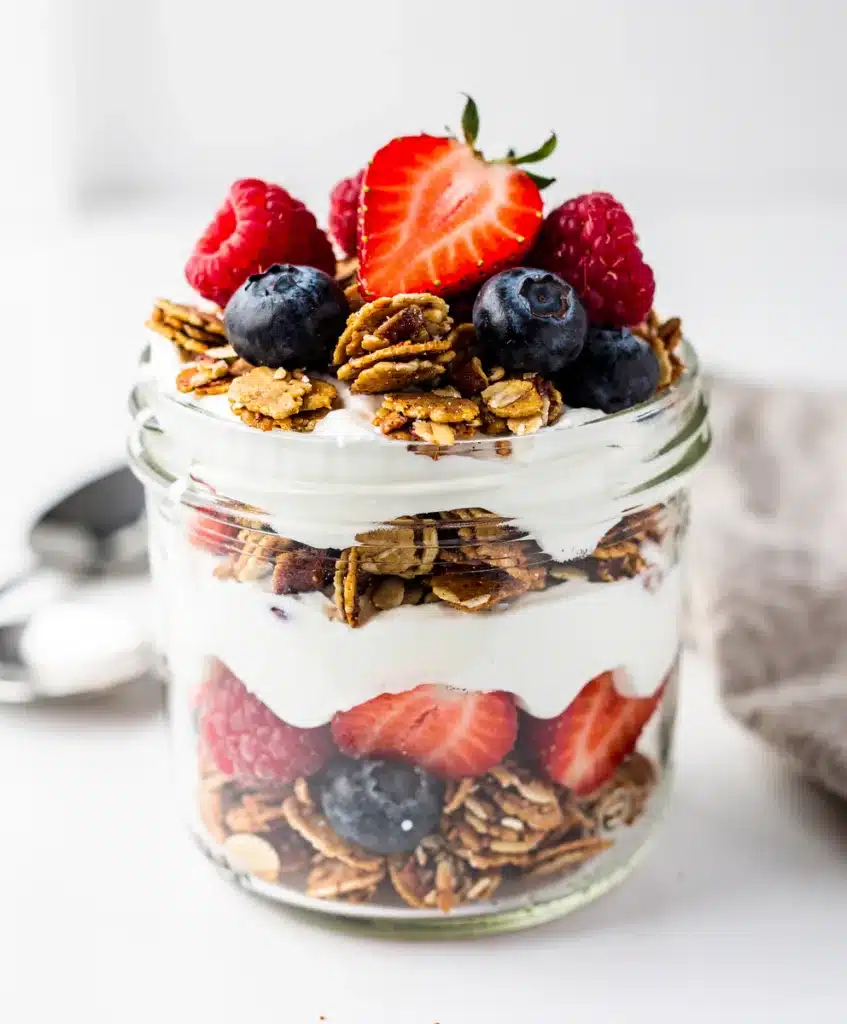 Greek yogurt parfait with granola and fresh berries in a glass jar.