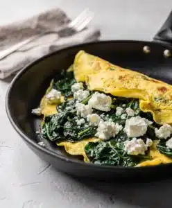 Spinach feta omelet recipe with creamy eggs and melted cheese close up