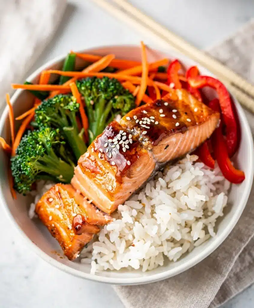 Flaky teriyaki salmon with broccoli and carrots over white rice.