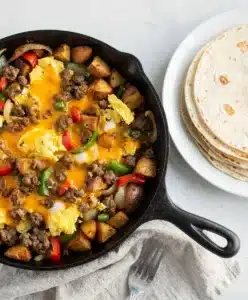 Hearty breakfast burrito skillet with sausage, eggs, potatoes, and melted cheese.