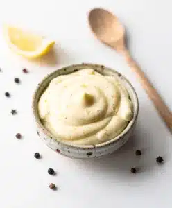 Creamy garlic aioli recipe in a rustic bowl with roasted garlic and lemon