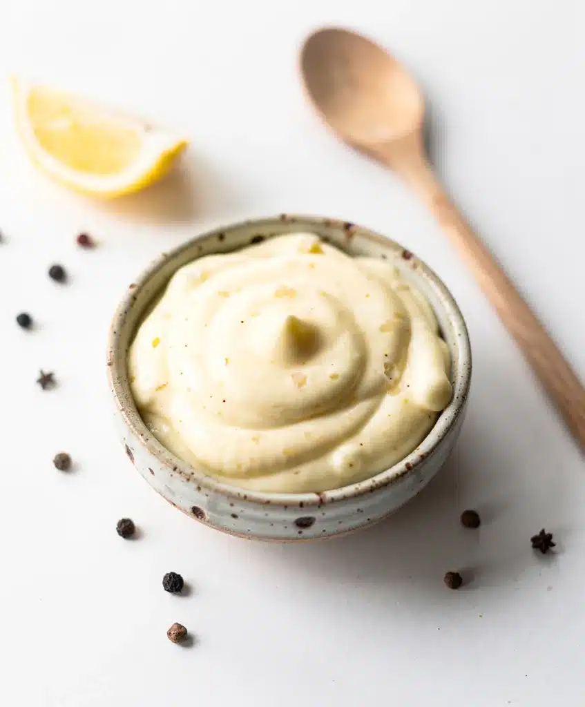 Creamy garlic aioli recipe in a rustic bowl with roasted garlic and lemon