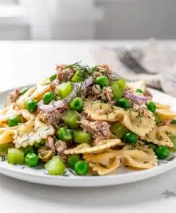 Creamy tuna pasta salad with bowtie pasta peas and celery in white bowl