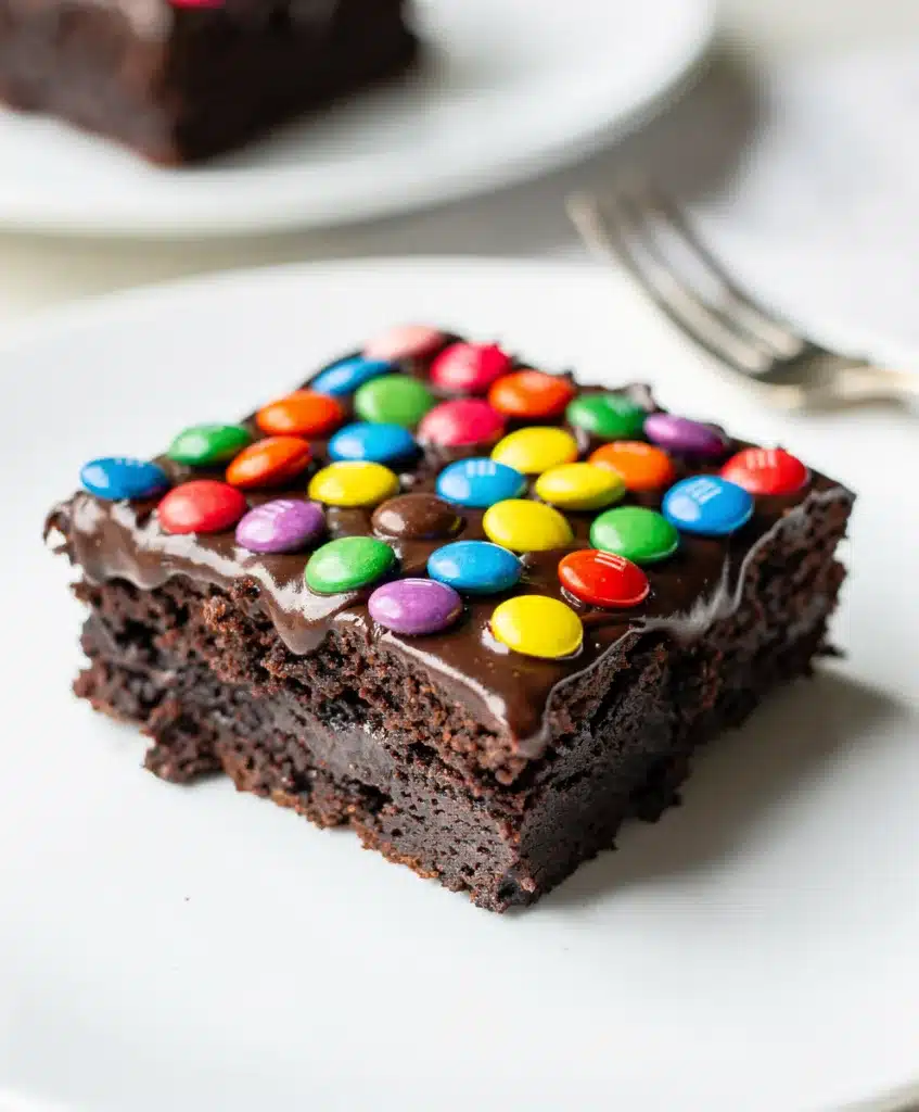 Fudgy cosmic brownies with glossy ganache and colorful candy sprinkles close up.