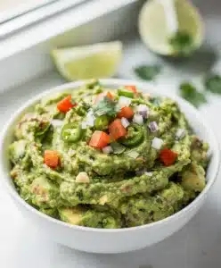 Creamy homemade guacamole with fresh lime in a rustic stoneware bowl.