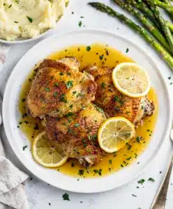 Crispy lemon garlic chicken thighs with a glossy pan sauce and fresh herbs.