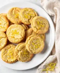 Golden lemon sugar cookies with crisp edges and soft crumb on rustic board.
