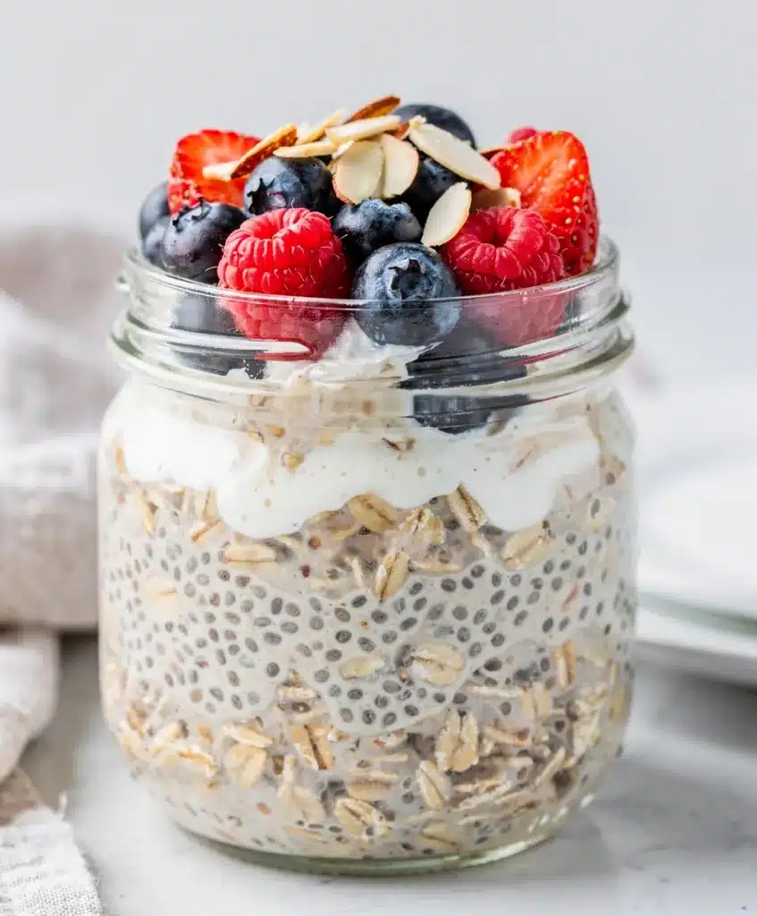 Morning overnight oats in a jar with fresh berries, chia seeds, yogurt, and honey.