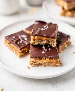 Perfect peanut butter chocolate bars with fudgy topping and oat base on marble counter.