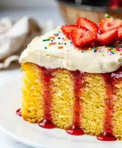 Moist yellow cake soaked with vibrant red strawberry gelatin and fluffy frosting
