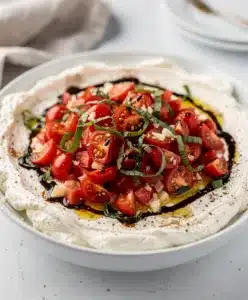 Creamy bruschetta dip with fresh tomatoes and basil on toasted bread.