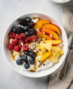 Vibrant cottage cheese fruit bowl topped with fresh berries and golden honey.