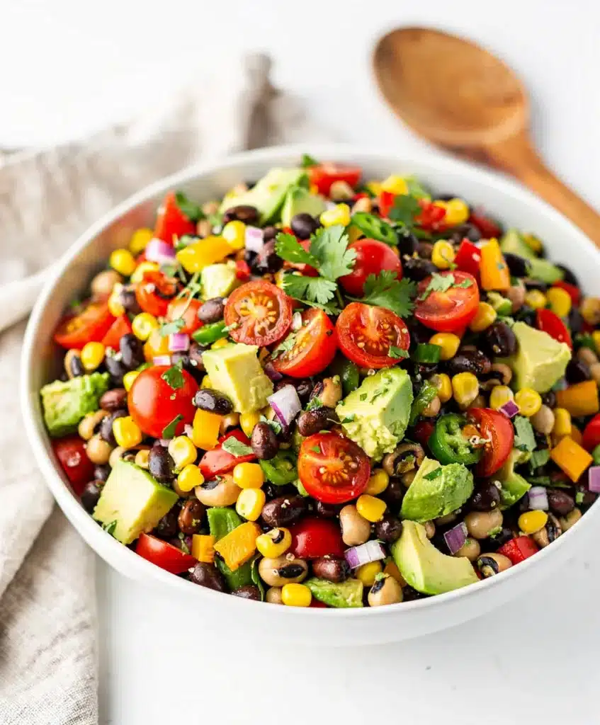 Cowboy caviar dip with avocado and beans in a rustic ceramic bowl