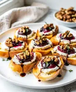 Rustic fig goat cheese crostini appetizer with jam and walnuts on slate.
