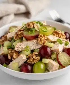 Creamy grape walnut chicken salad in a white bowl on rustic wood