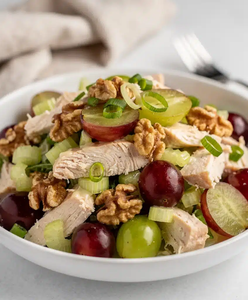 Creamy grape walnut chicken salad in a white bowl on rustic wood