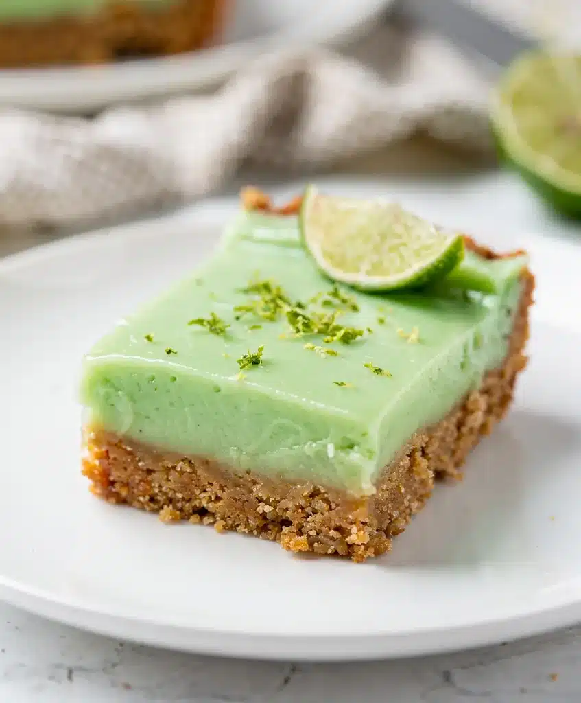 Creamy key lime pie bars with whipped cream on a rustic wood background.