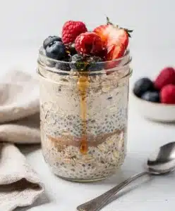Creamy overnight protein oats in a jar topped with fresh berries and chia seeds.