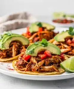 Shredded chicken tacos with cilantro, onion, and cotija cheese.