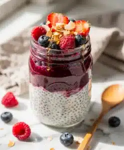 Creamy layered chia pudding with mixed berry compote in jar