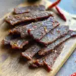 finished best beef jerky close-up with red pepper flakes on wood