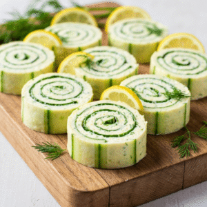 Creamy cucumber dill pinwheels recipe on a rustic wooden board.