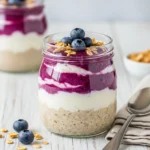 High protein blueberry cheesecake oats in a glass jar with granola.