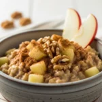 Creamy high fiber apple cinnamon oatmeal with walnuts in a rustic bowl.