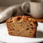 Moist brown butter banana bread slice with melting butter and banana pieces.