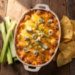 Golden bubbly RedHot Buffalo Chicken Dip with blue cheese and celery.