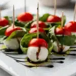 Colorful Caprese skewers with balsamic glaze on a rustic wooden board.