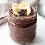 Creamy chocolate chia overnight oats in a jar with almond butter and fruit.
