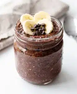 Creamy chocolate chia overnight oats in a jar with almond butter and fruit.