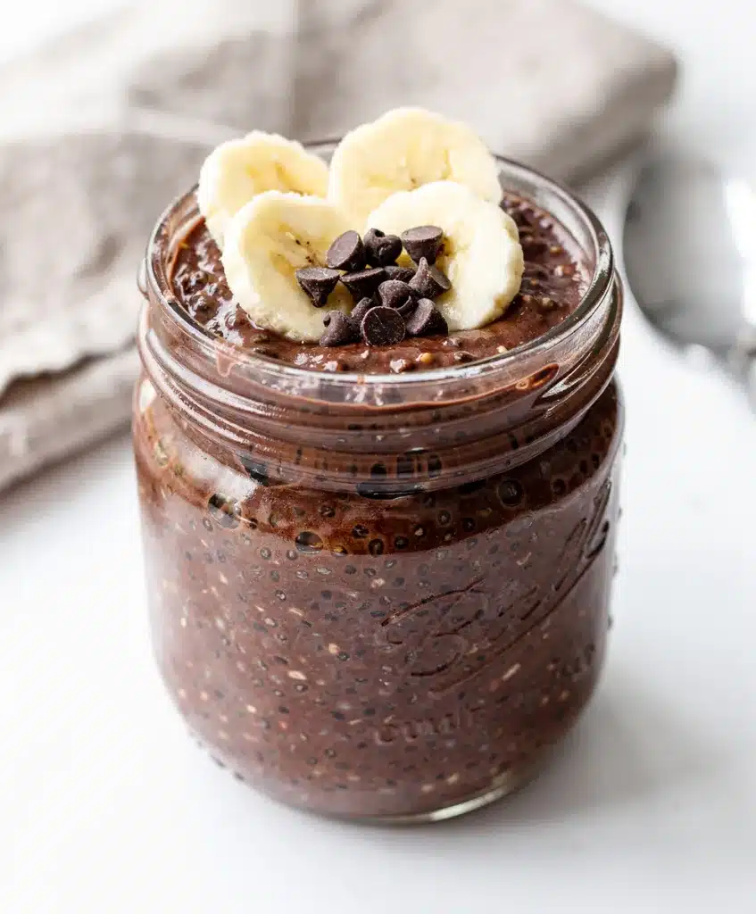Creamy chocolate chia overnight oats in a jar with almond butter and fruit.