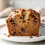 Moist chocolate chip banana bread slice with melty chips on rustic table