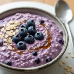 Creamy blended tofu and blueberry oats in a rustic ceramic breakfast bowl.