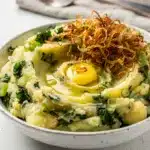 Creamy colcannon potatoes with kale and green onions in a rustic bowl.