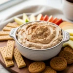 Creamy gingerbread cheesecake dip with festive cookies and apple slices for dipping.