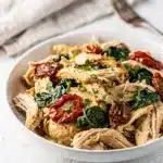 Creamy Tuscan chicken with spinach and sun-dried tomatoes in a rustic bowl.