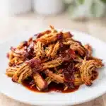 Saucy crockpot BBQ pulled chicken on a toasted bun with fresh coleslaw.