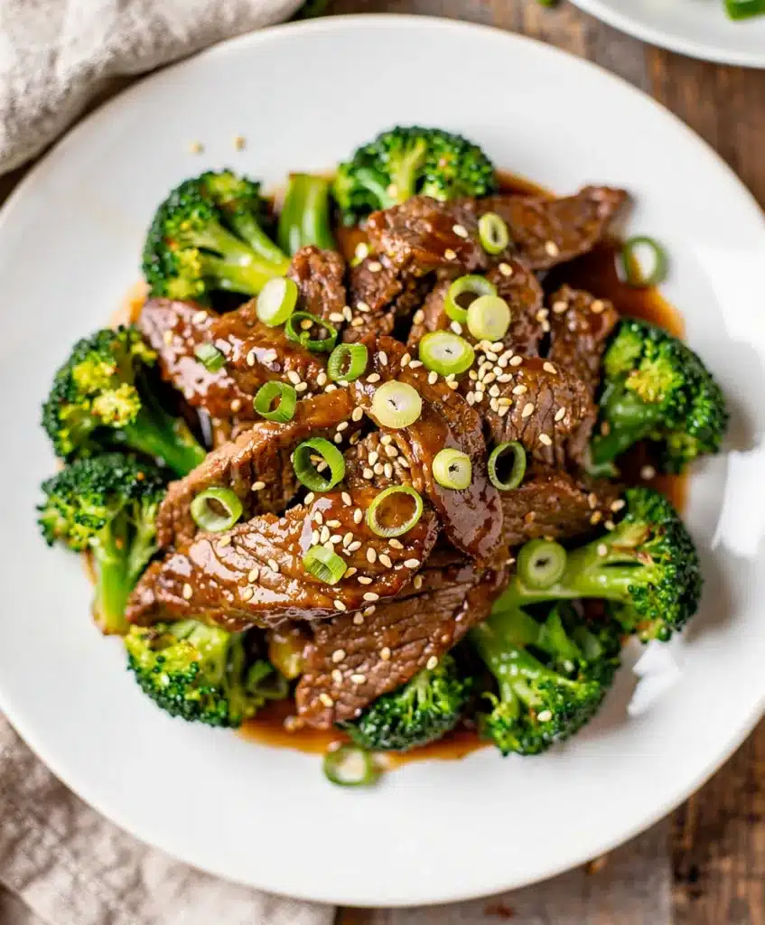 Crockpot beef and broccoli with rice in a white bowl on wood.