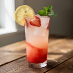 A blush pink Cupid's lemonade mocktail garnished with fresh fruit and mint.