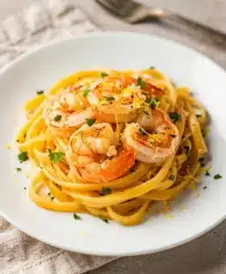 Creamy garlic butter shrimp pasta with lemon and parsley on white plate