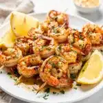 Garlic butter shrimp skewers with parsley and lemon on rustic platter